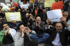 Teachers, health workers and local civil servants shout as part of a a three-day strike over plans to tighten spending and increase the retirement age as part of the 2017 finance bill, Monday Nov.21, 2016 in Algiers. The government, coping with a fall in oil revenue, wants to raise taxes, freeze some salaries and set a minimum retirement age of 60. Poster at right reads: No to attacks on unions rights and striking right. (AP Photo/Sidali Djarboub)